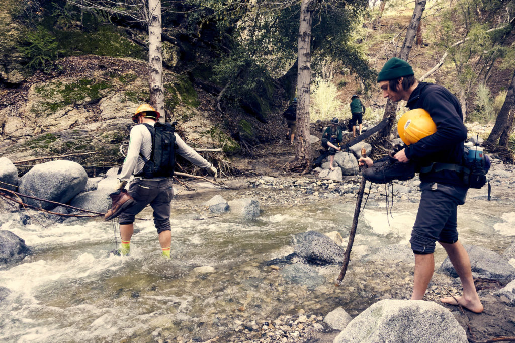 Two volunteers wading across a river.